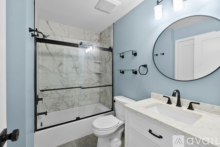 A bathroom with a marble shower and white toilet.
