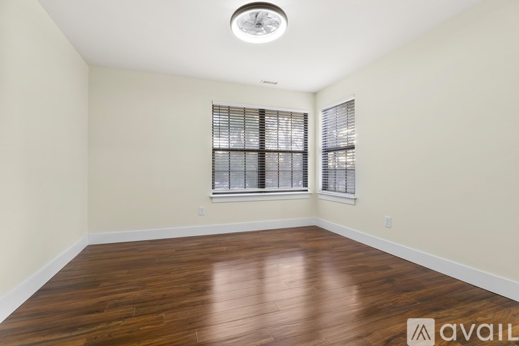 A room with wooden floors and a window with blinds.
