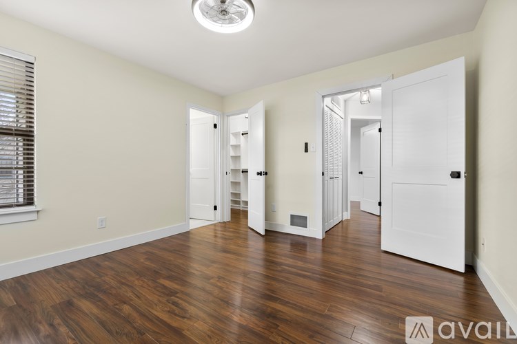 A room with wooden floors and white walls, with a door on the right side.