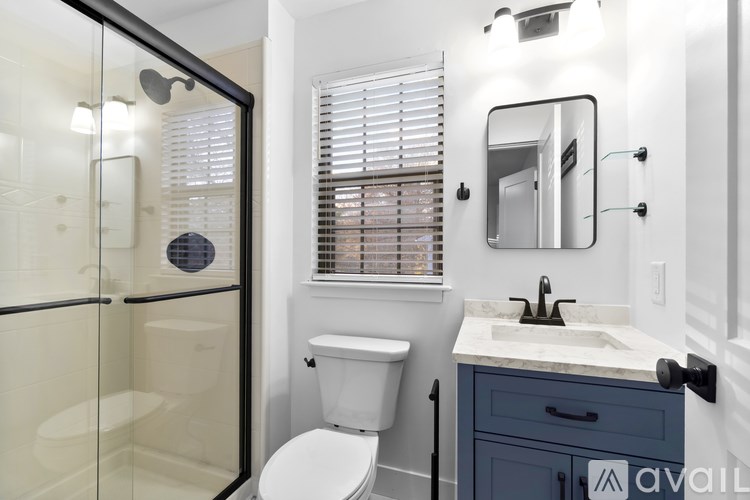 A bathroom with a white toilet, a sink, and a glass shower stall.