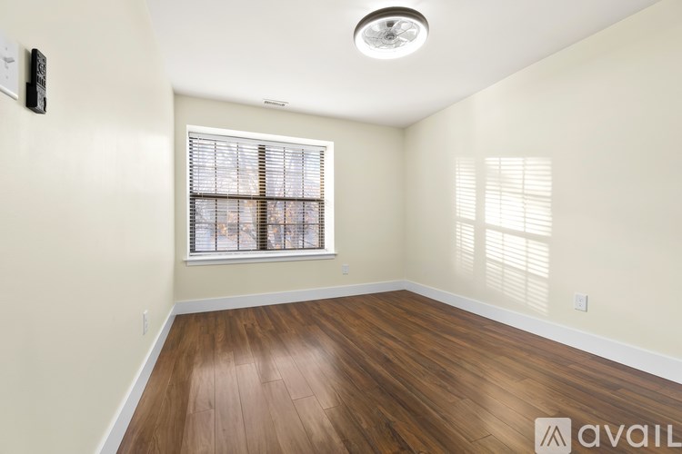 A room with wooden flooring and a window with blinds.