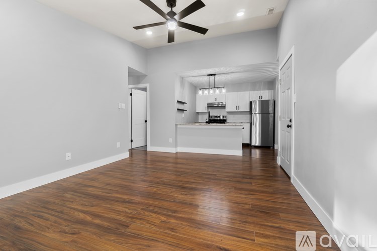 A spacious kitchen with white cabinets and a wooden floor.
