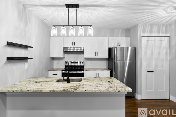 A modern kitchen with a marble countertop and stainless steel appliances.