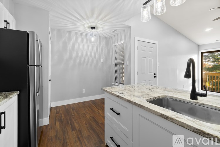 A kitchen with a black refrigerator and a marble countertop.