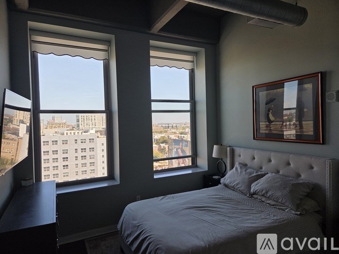 A bedroom with a large bed and a window overlooking a cityscape.