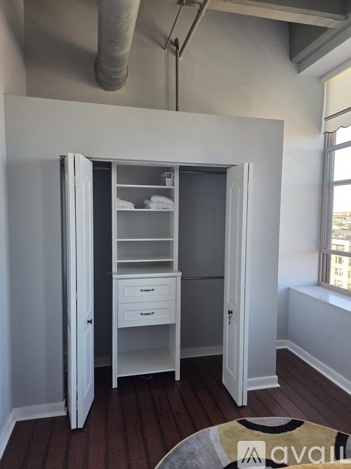 A white closet with a shelf and drawers is open in a room.