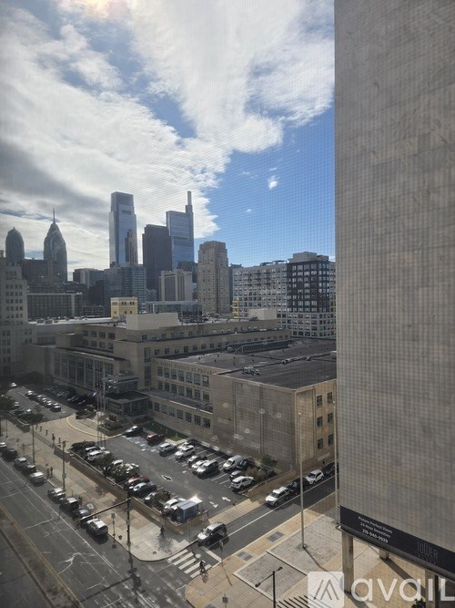 A cityscape with tall buildings and a parking lot in the foreground.