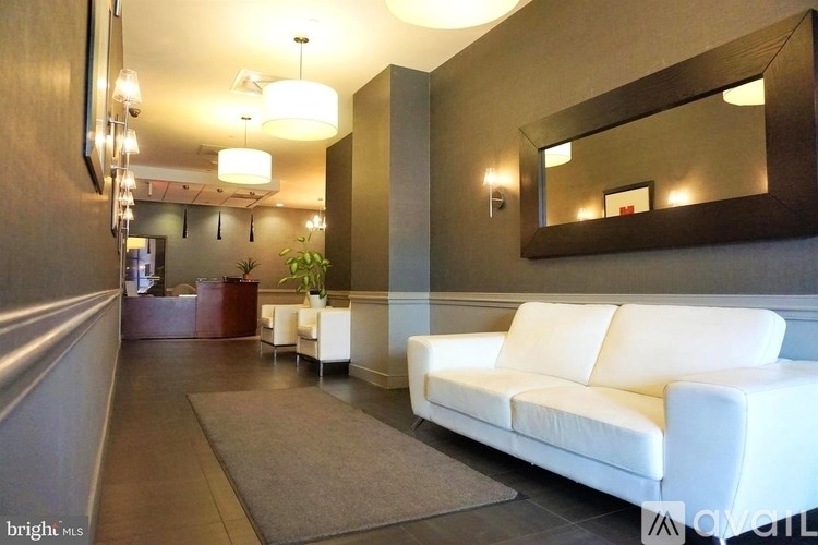 A white couch is in front of a mirror in a well-lit room.