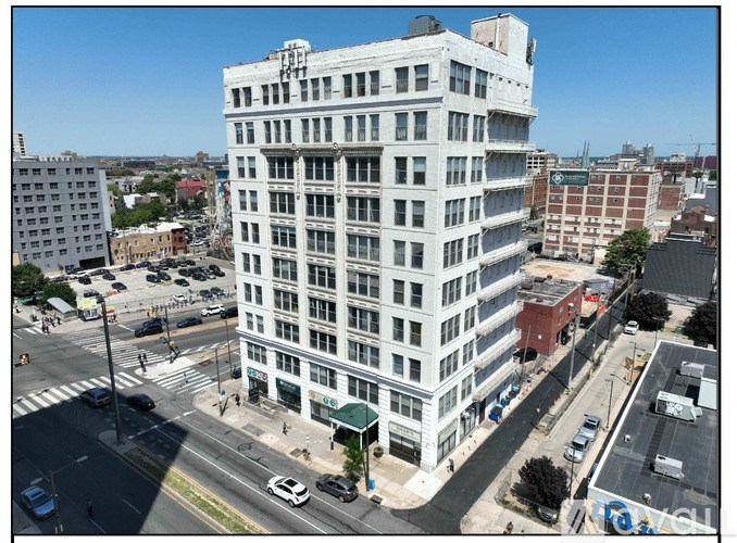 A tall white building with many windows is in the middle of a city street.