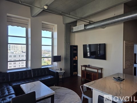 A living room with a black leather couch and a television.