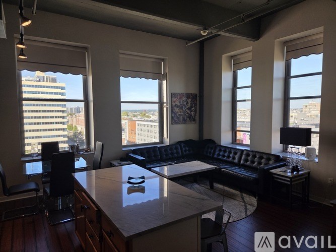 A living room with a couch, chairs, and a table with a lamp on it.