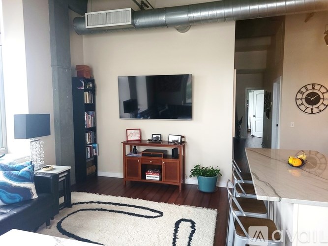 A living room with a television, a bookshelf, and a plant.
