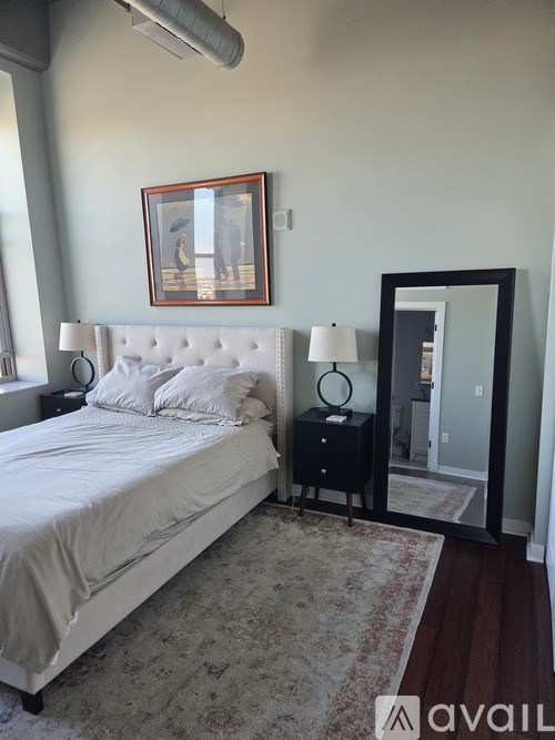 A bedroom with a bed, nightstand, and a painting on the wall.