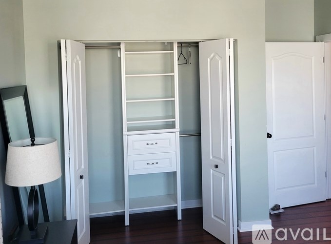 A white shelving unit with a drawer and shelves is in a room.