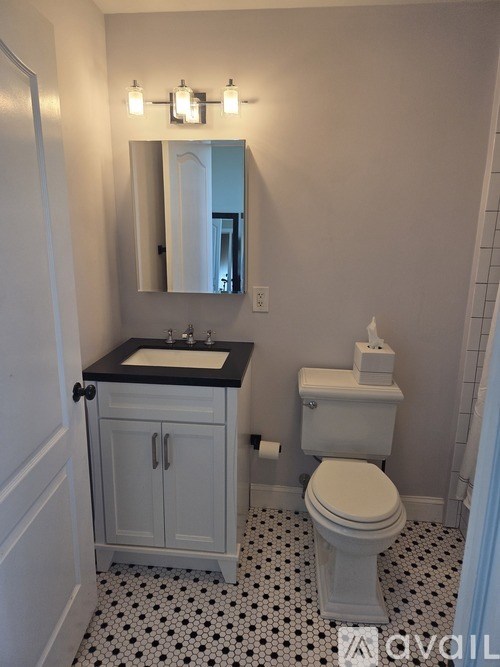 A white toilet sits in a bathroom with a black and white floor.