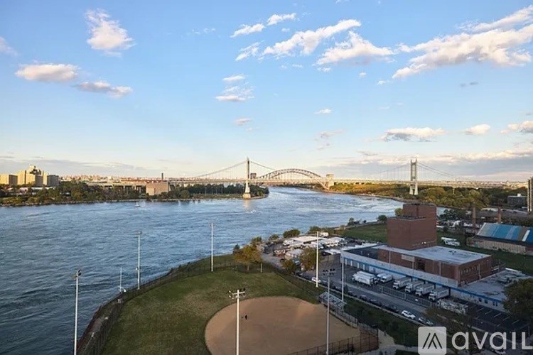 A bridge over a river with a building and a baseball field in the foreground.