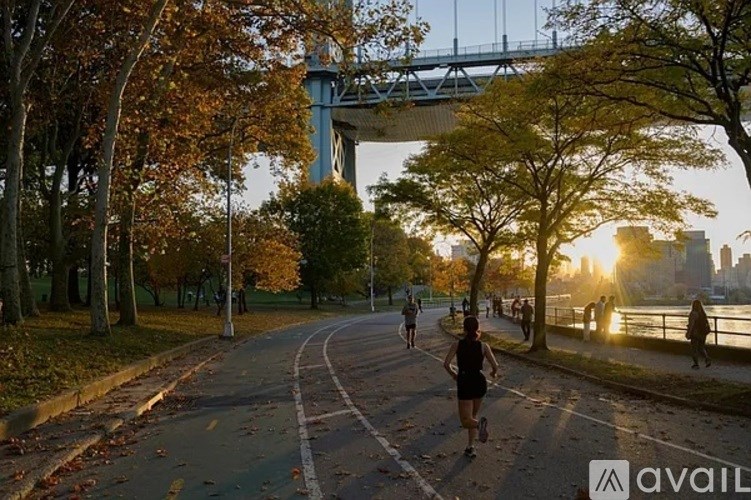 A person is running on a path near a river with a bridge in the background.