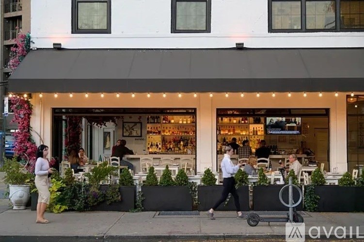 A woman in a white shirt is walking past a storefront with a sign that reads "available."