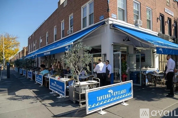 A row of Taverna Restaurant tables are set up on the sidewalk.