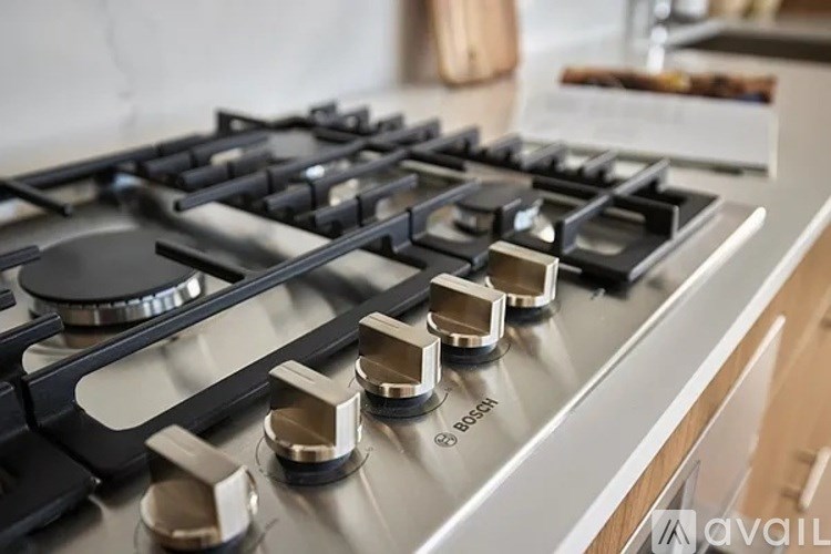 A close up of a modern gas stove with a silver finish and black knobs.