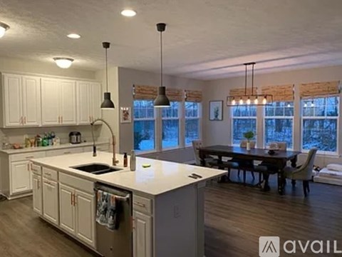 A kitchen with white cabinets and a large island with a sink.