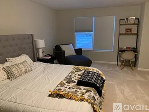 A bedroom with a bed, a chair, and a window.