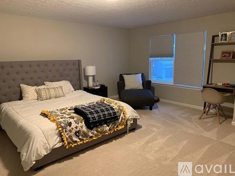 A bedroom with a bed, chair, and window.
