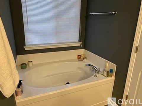 A white bathtub is in a bathroom with a white towel hanging on the side.