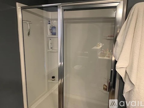 A bathroom with a glass shower door and a white towel hanging on the door.