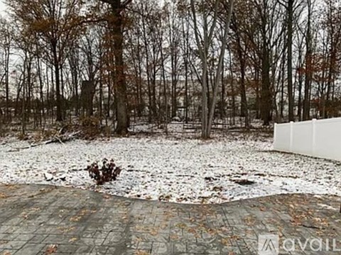 A snowy landscape with a white fence and bare trees.
