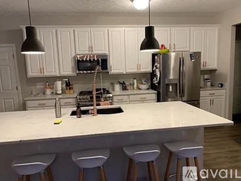 A kitchen with white cabinets and a large island with three stools.