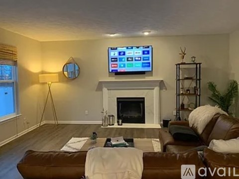 A living room with a fireplace, a couch, and a television mounted above it.