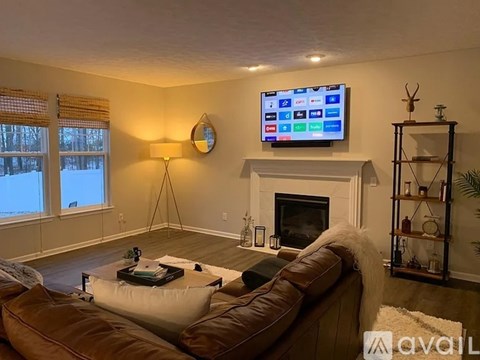 A living room with a couch, a fireplace, and a television mounted above it.