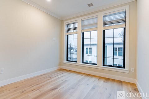 A room with wooden floors and a large window with blinds.
