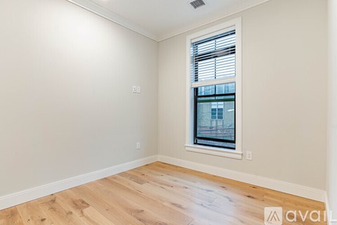 A room with wooden flooring and a window with blinds.