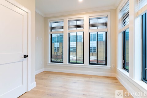 A room with a white door and three windows with blinds.