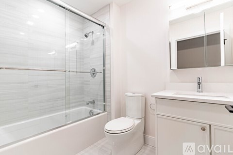 A white bathroom with a glass shower enclosure and a toilet.