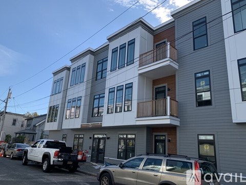 A row of townhouses with cars parked in front.