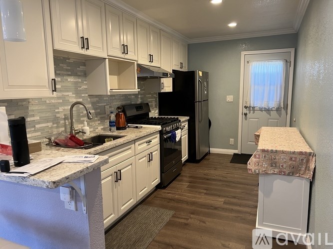 A kitchen with white cabinets and a black fridge.
