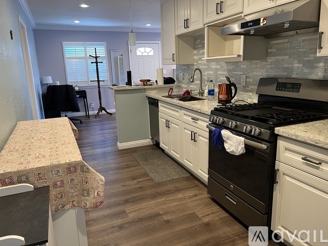 A kitchen with a black stove top oven and white cabinets.