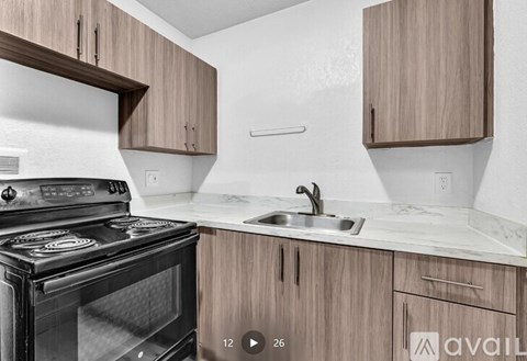 A kitchen with a black stove and wooden cabinets.