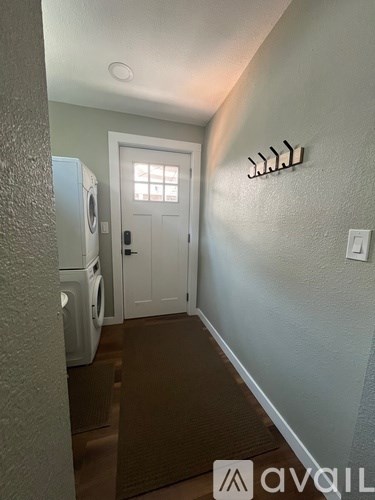 A hallway with a washing machine on the left and a door in the middle.