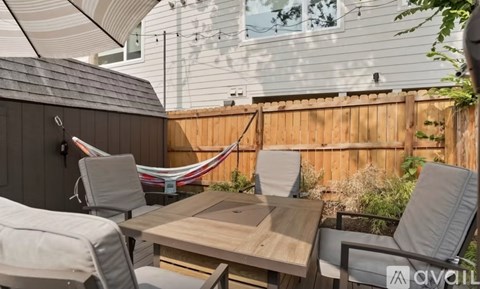 A patio with a table, chairs, and a hammock.