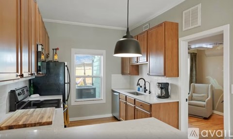 A kitchen with wooden cabinets and a black refrigerator.