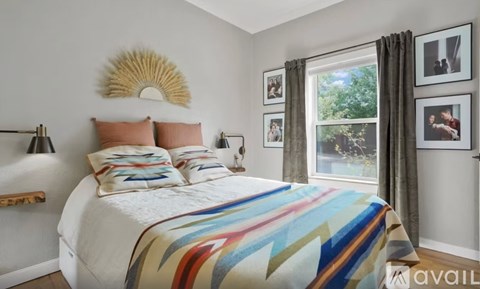 A bedroom with a white bed and a colorful blanket.