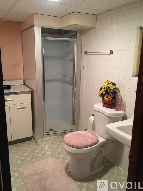A bathroom with a pink toilet seat and a flower pot on the toilet.