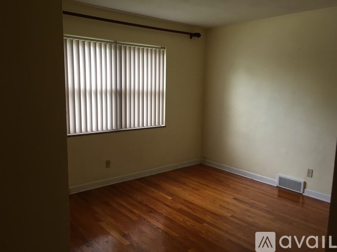 A room with wooden floors and a window with blinds.