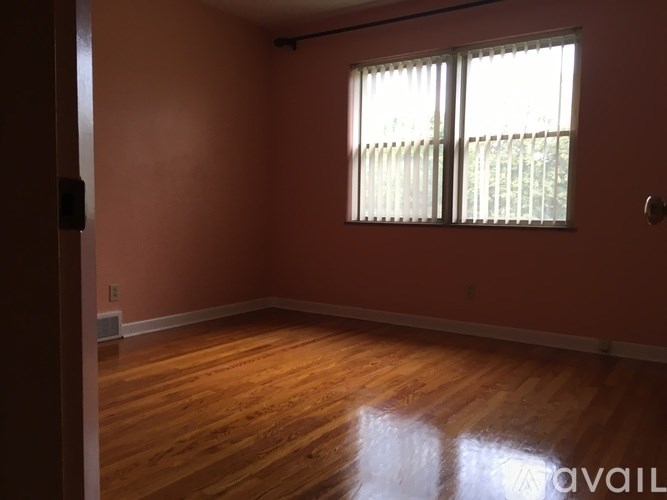 A room with wooden floors and a window with blinds.