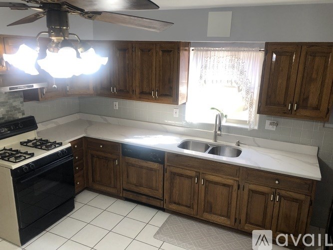 A kitchen with a stove, sink, and cabinets.
