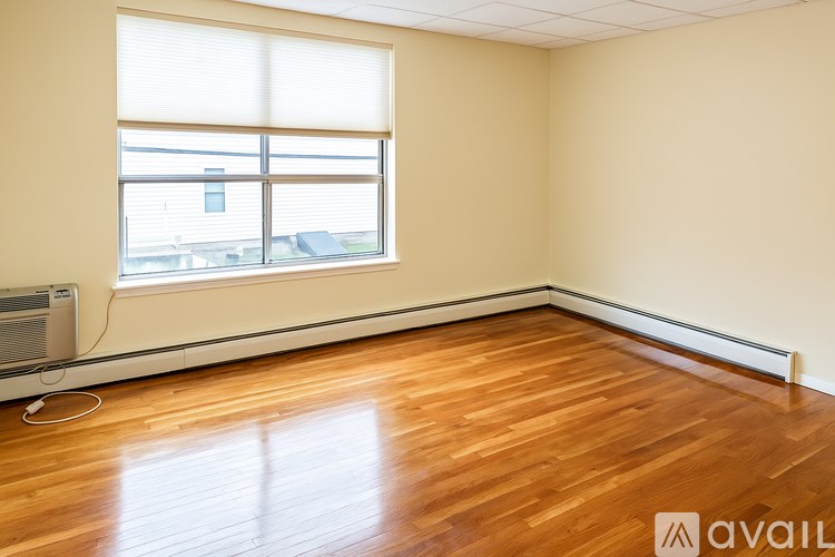 A room with wooden flooring and a window with blinds.